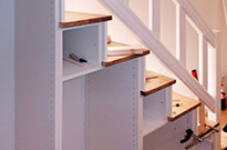 Konstruktion von Treppenschrank mit beleuchteten Stufen, Türen und Auszügen, einseitger Handlauf optisch aufgewertet mit Nuten, weiß lackiert