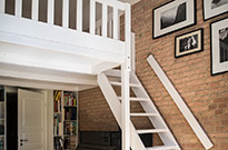 Bild 224: Hochetage, weiß lackiert, Geländer mit Querlattung, große Treppe mit Handlauf, Konstruktion mit nur einem Standbalken, Trägerbalken längs an der Wand