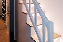 Bild 267: Treppenschrank mit beleuchteten Stufen, Türen und Auszüge / Schubkästen nach individuellen Vorgaben, einseitger Handlauf optisch aufgewertet mit Nuten, weiß lackiert